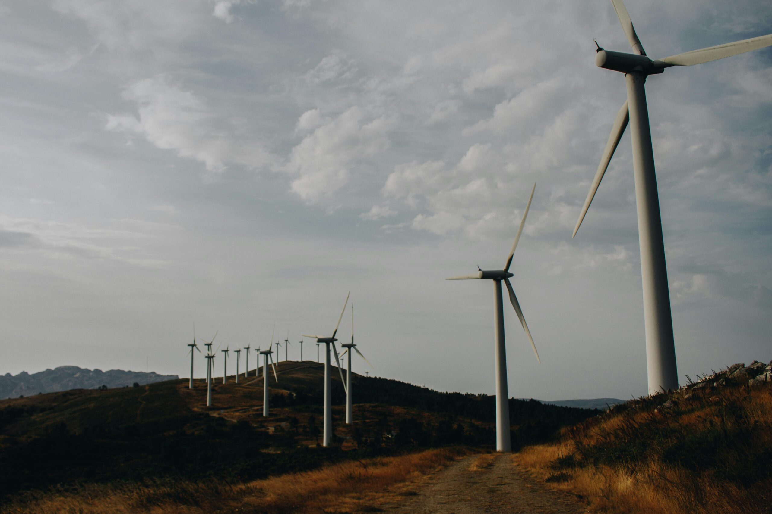 A scenic view of wind turbines on a hill during a cloudy day, highlighting renewable energy.